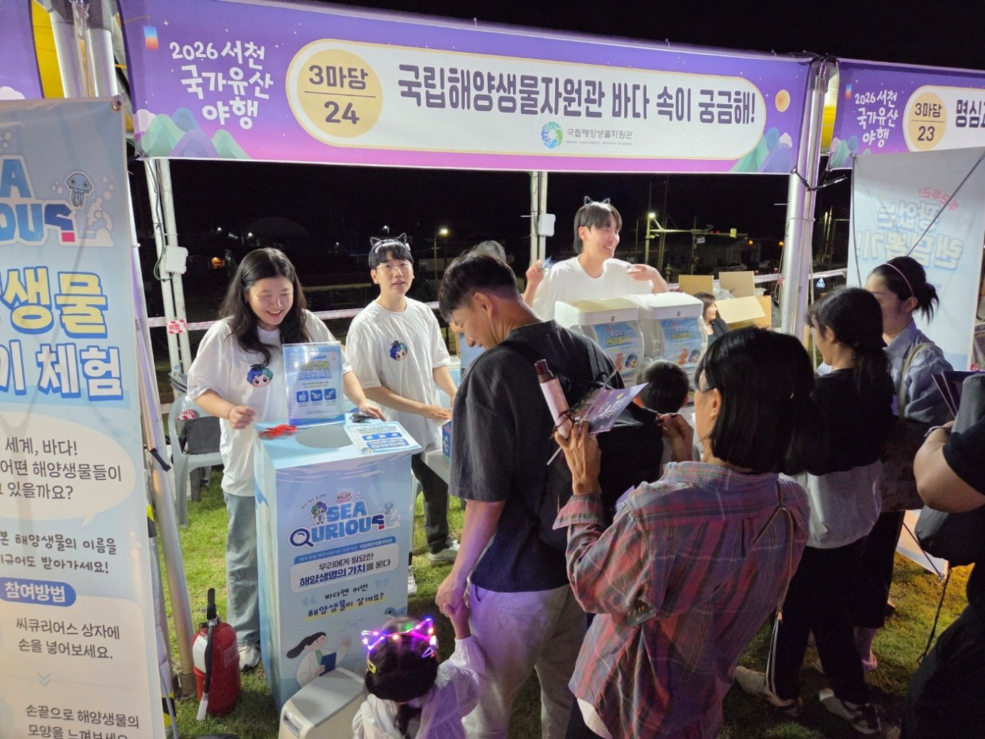 야간에 불을 밝힌 국립해양생물자원관 홍보부스에서 관람객을 맞이하는 직원들